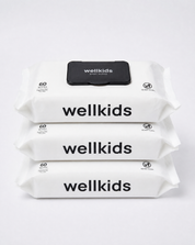 Three stacked packs of Wellkids baby wipes on a clean white background. The packs are white with bold black text reading 'wellkids' and a small black flap on top showing the brand name.